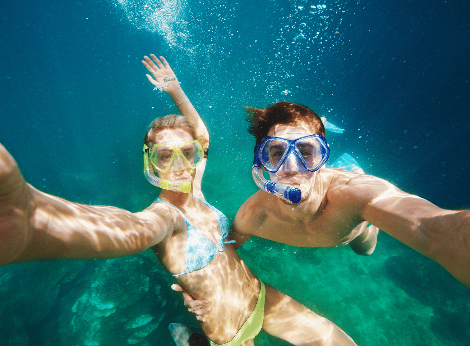 Two people snorkeling underwater, taking selfie.