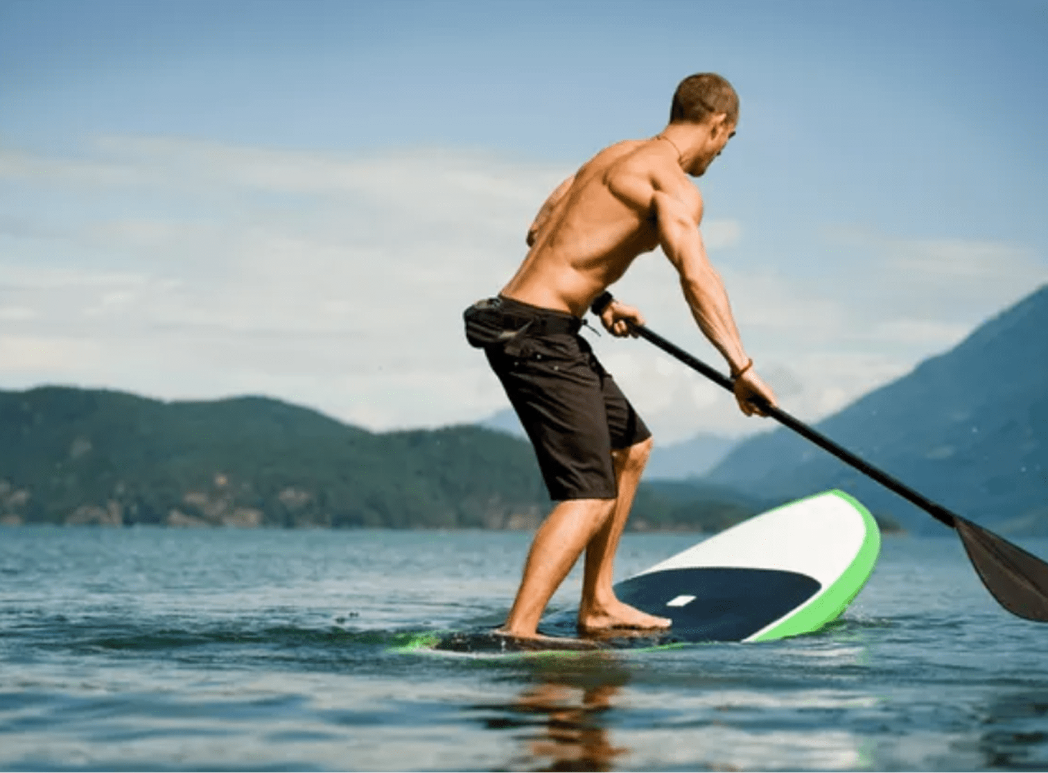 Man paddleboarding on a calm lake.